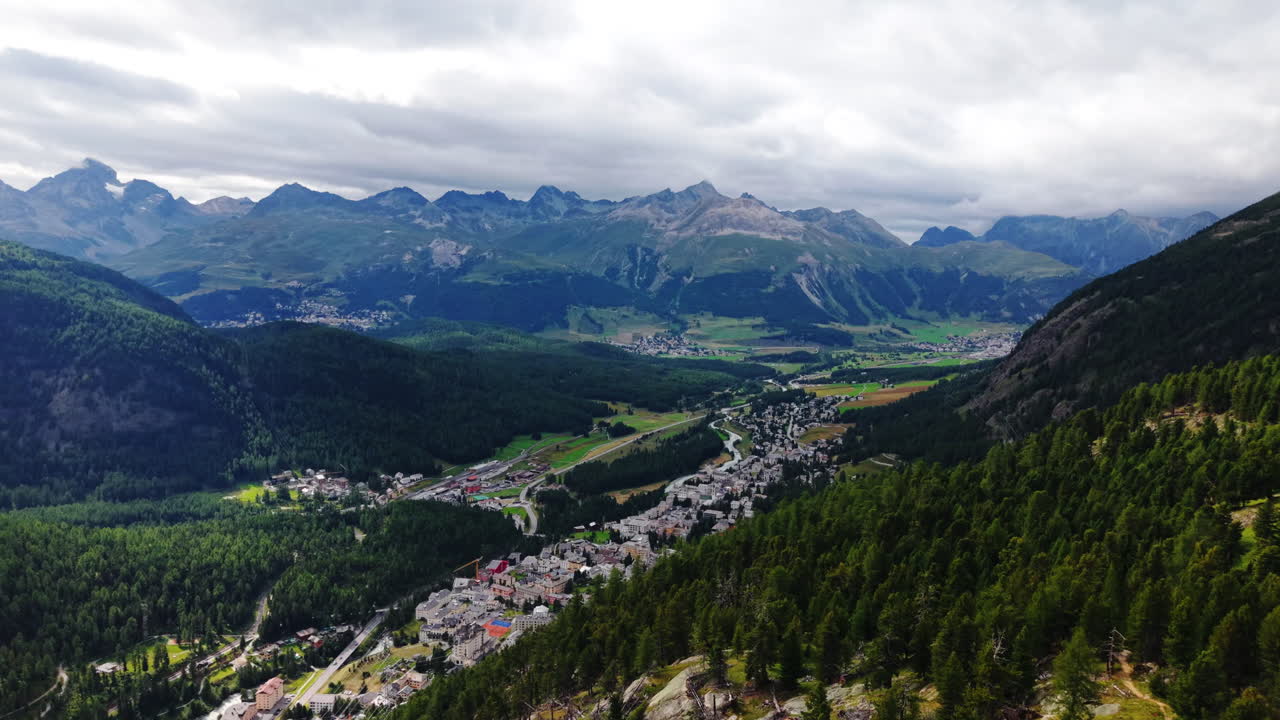 Forward drone flight along mountain slope overlooking valley and cloudy Swiss peaks