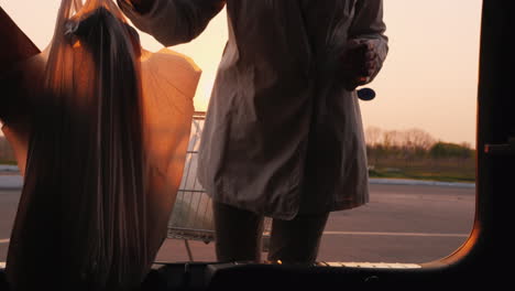 young woman puts shopping bags in the trunk of a car