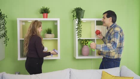 Happy-couple-cleaning-their-house-while-chatting-with-pleasure.