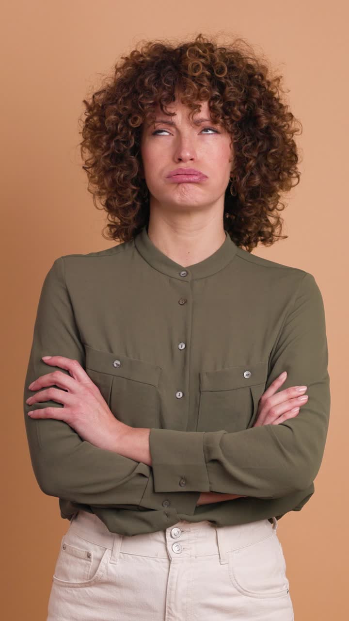 Disagreeing young woman shaking head with twisted mouth on beige background. Vertical orientation