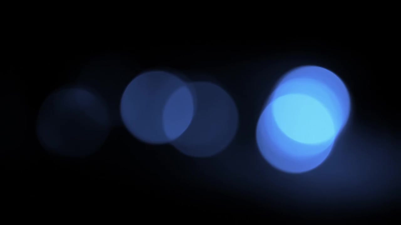 Luci bokeh blu che appaiono e scompaiono su sfondo nero