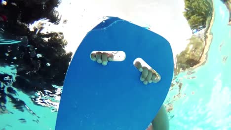 boy floating on surfboard at swimming pool