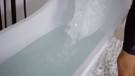 man filling bath with ice cubes