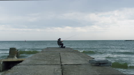 fisherman fishing using rod on sea bridge construction in spring beach coastline