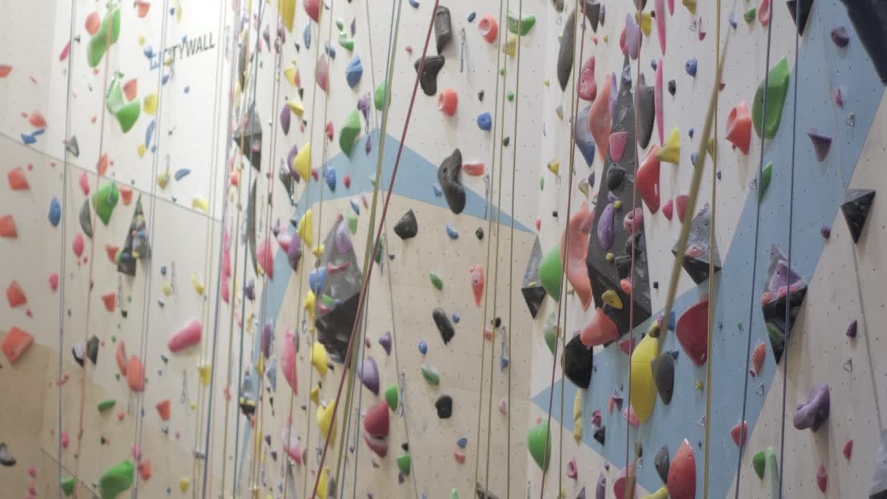 una foto amplia de una pared de un gimnasio de escalada interior vibrante