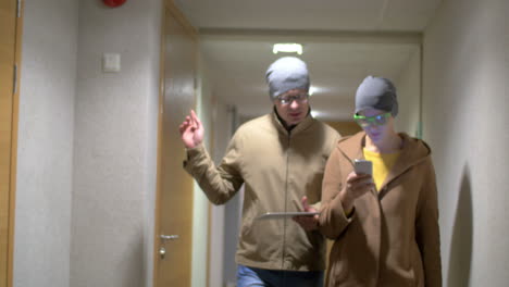 Hipster friends with pad and cell walking in hotel hall