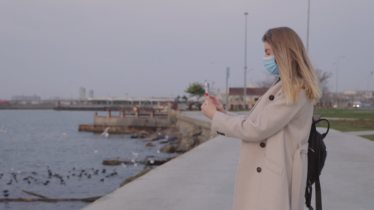 Vrouw die een foto maakt aan zee met mondkapje