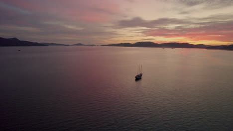 toma aérea de un pequeño bote anclado en el mar con una impresionante puesta de sol