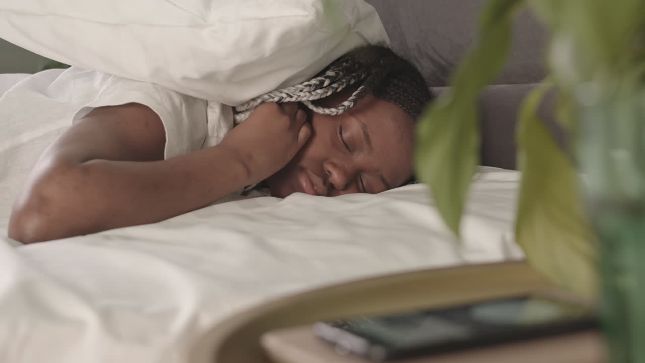 Sleepy African American Woman Turning off Alarm on Phone