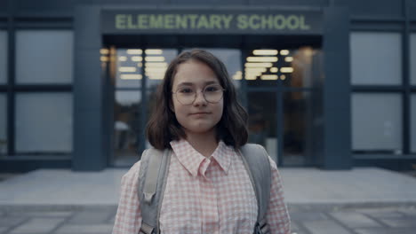 serious school girl standing on schoolyard closeup. teen brunette looking camera