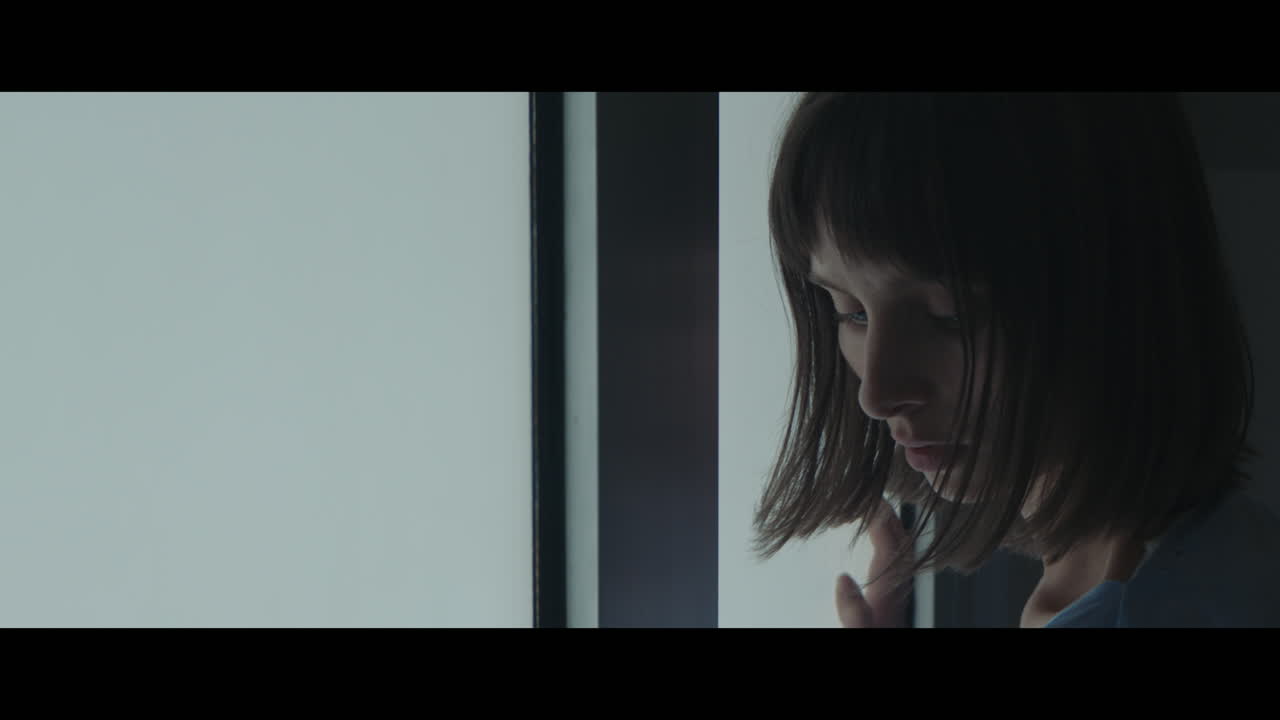 A girl near the milky glass door ctahces a moment