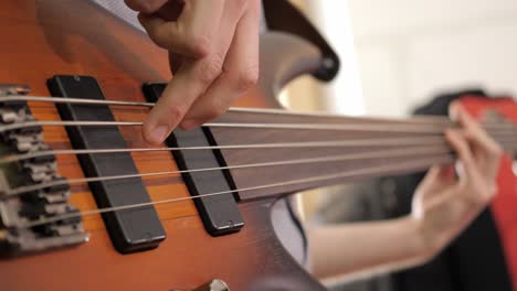 Close-up-of-a-professional-bass-guitar-player,-playing-finger-style-on-a-fretless-bass-during-a-recording-session