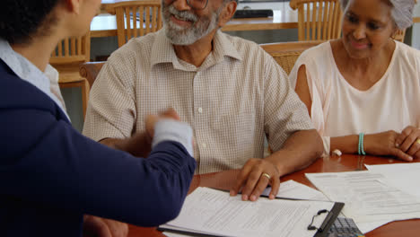 Mixed-race-female-real-estate-agent-discussing-over-property-with-senior-couple-at-home-4k