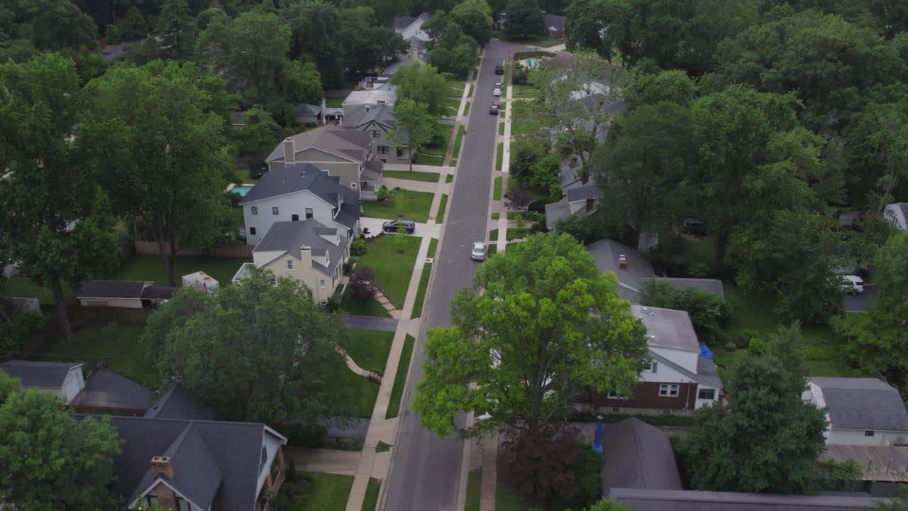 Aerial descent from high above a nice suburban neighborhood down to sidewalk and green grass