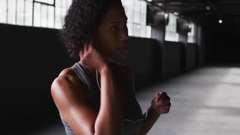 portrait of african american woman standing in an empty building putting earphones in