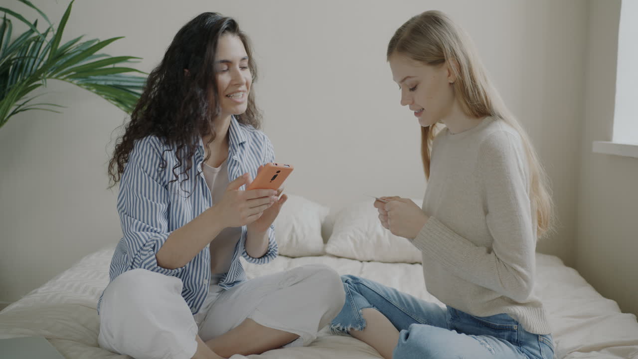 Two women using a phone and credit card