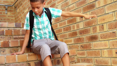 Trauriger-Schuljunge,-Der-Allein-Auf-Der-Treppe-In-Der-Schule-Sitzt