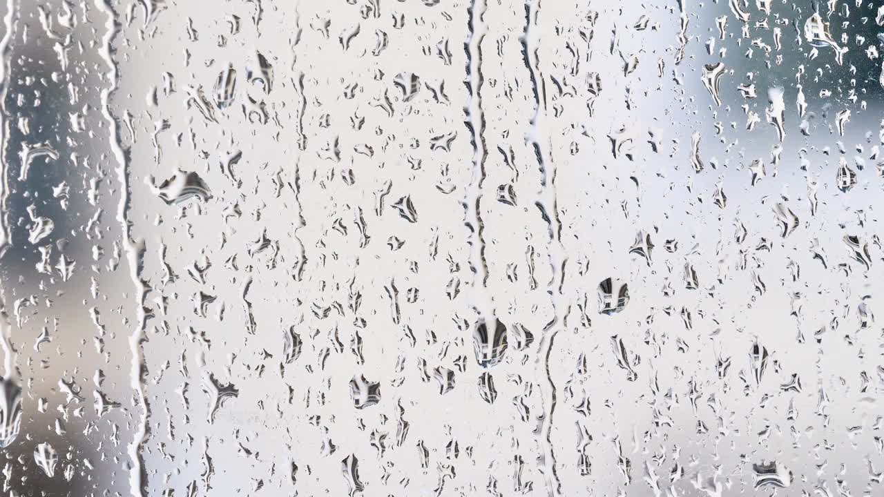 gotas de lluvia en la superficie de los vidrios de la ventana con el fondo del edificio borroso, película 4k, cámara lenta.