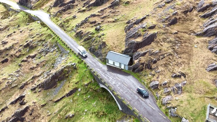 İrlanda'nın destansı konumları ve yol gezileri: Vahşi Atlantik Yolu üzerinde, Healy Geçidi'nin zirvesinde park etmiş bir arabayı geçen bir karavan.