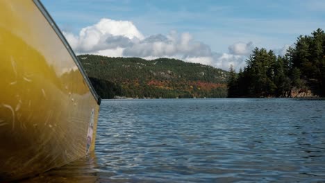 yellow canoe floats in blue lake waves, autumn outdoor wide tilt up