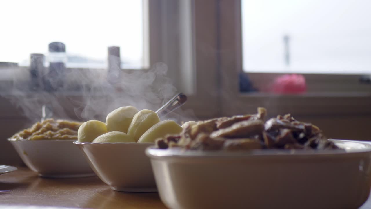 Hot steaming bowls of food on kitchen surface to be served