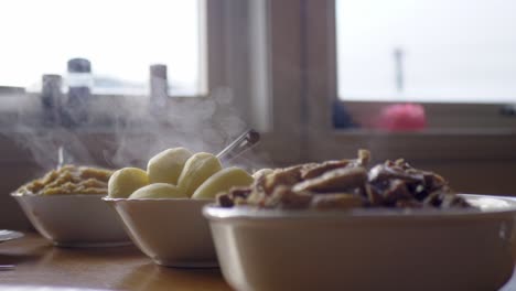 hot steaming bowls of food on kitchen surface to be served