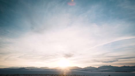 sunset over mountain range at white sand dunes covered in footprints