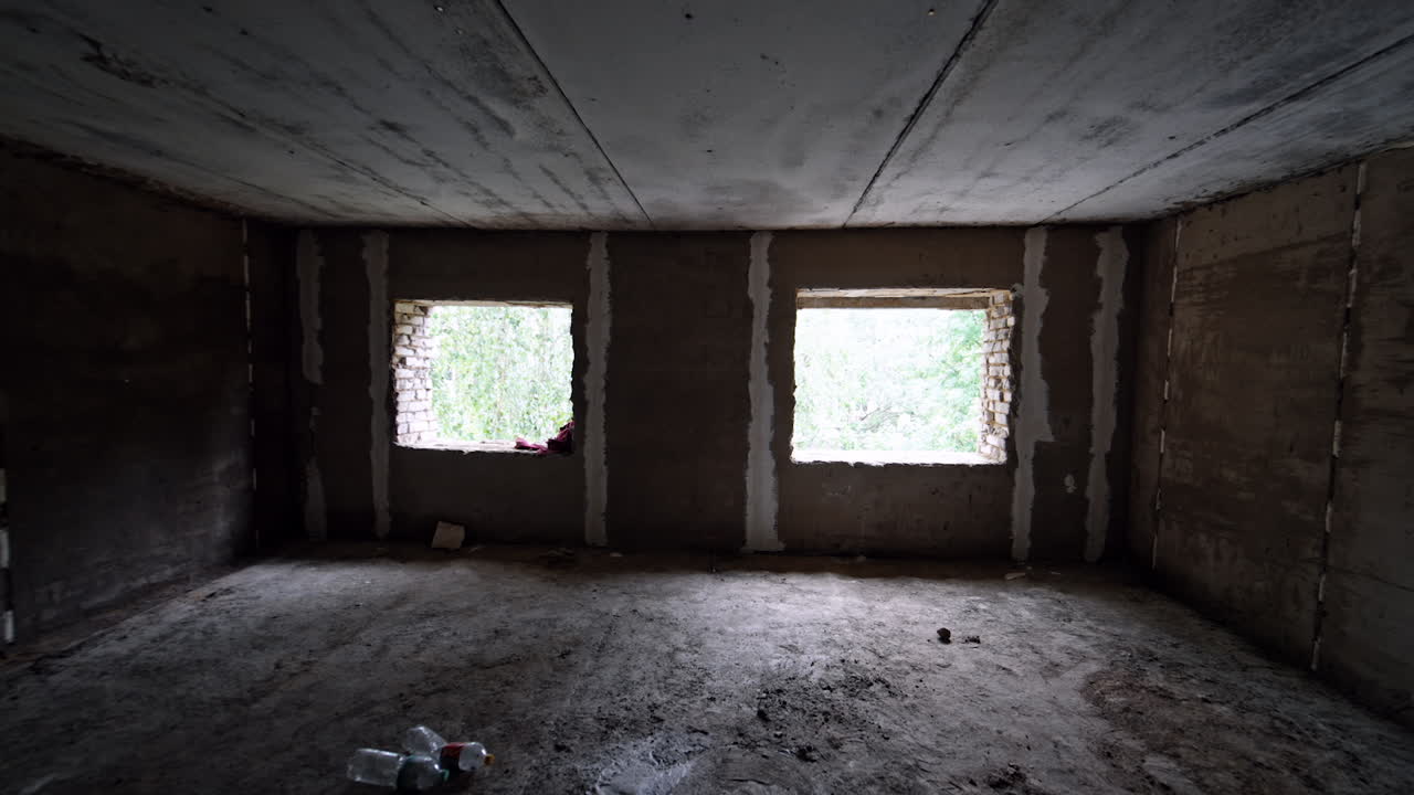 Interior of a large room with no works done inside. Premise with two holes prepared for windows.