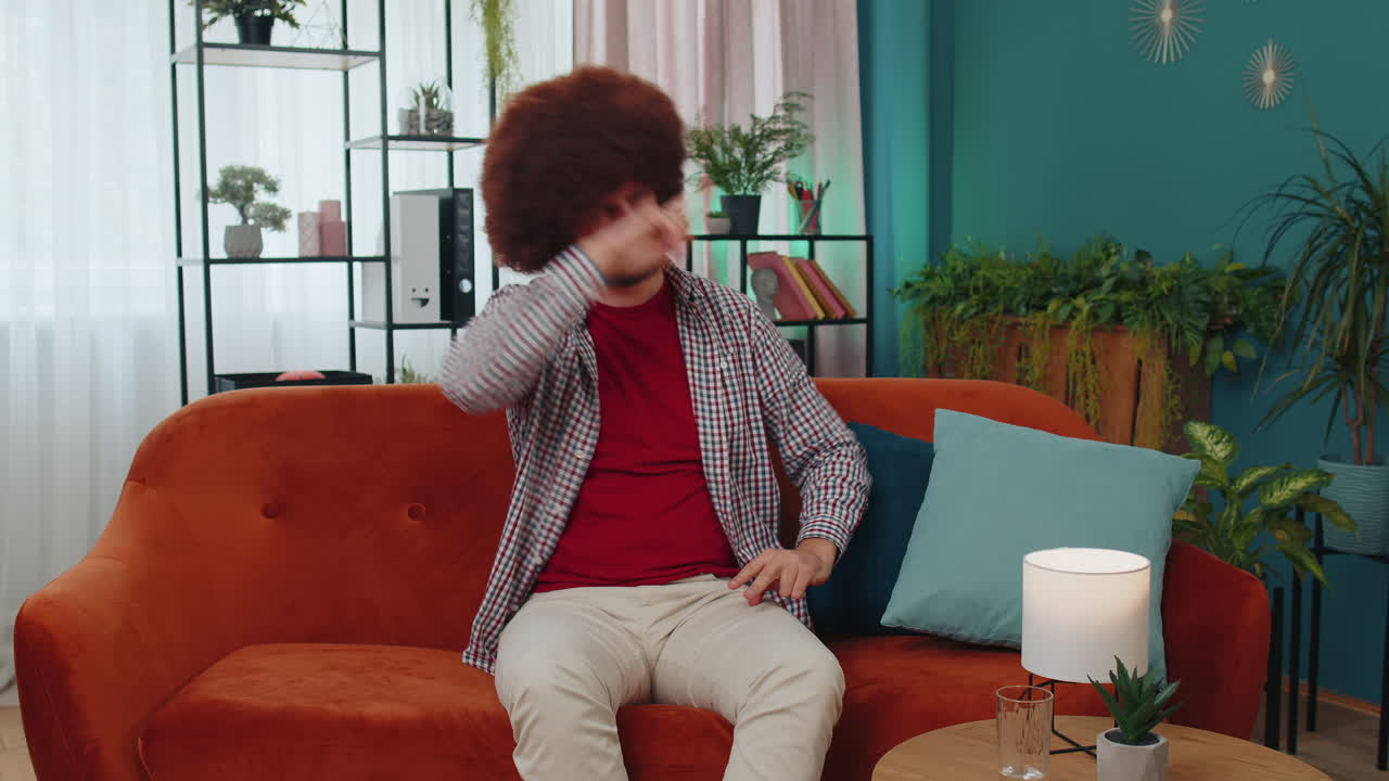Trendy cheerful positive man dancing and moving to rhythm making dub dance gesture at modern home