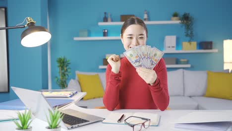 젊은 아시아 여성은 집에서 벌어들이는 돈을 보고 행복합니다.