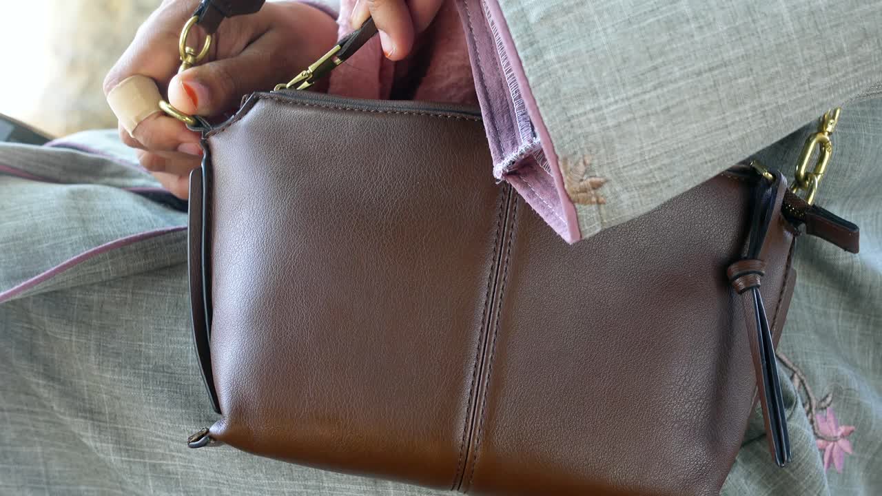 Woman holding a brown leather handbag