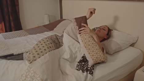 mujer acostada en su cama despertando lentamente en un lujoso dormitorio