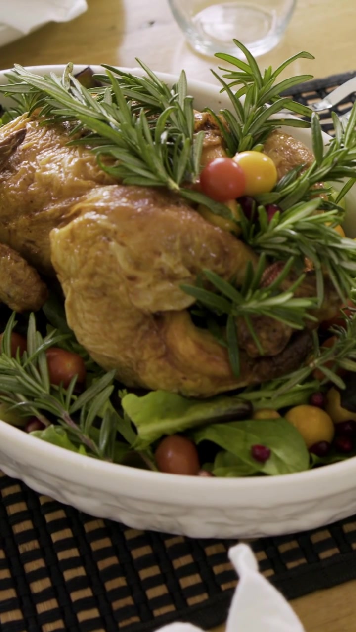 Video verticale: La telecamera panoramica su pollo arrosto in un piatto ovale sul tavolo da pranzo di casa che mostra mais