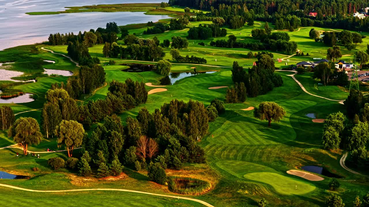 Lush green golf course by a lake with trees and scenic landscape