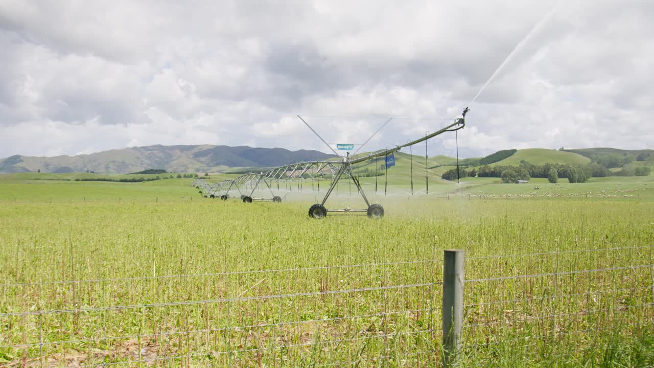 An irrigation truss on wheels watering a field of crops in Canterbury New Zealand on a cloudy day