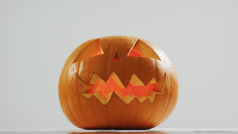 Close-up-view-of-scary-face-carved-halloween-pumpkin-against-grey-background