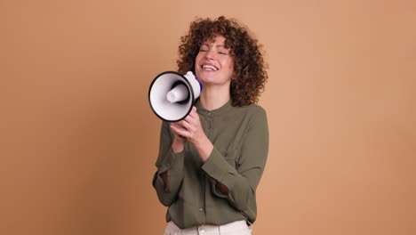 excited young woman screaming on loudspeaker in beige studio