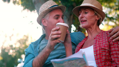 una pareja de turistas felices sentados en un banco sosteniendo un mapa