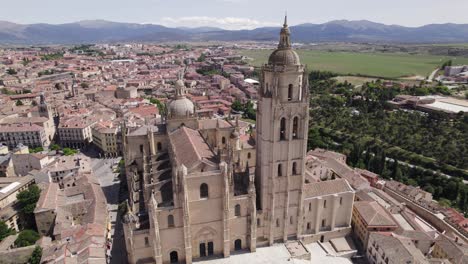 Closeup-aerial-orbit-of-Segovia-Cathedral,-vast-countryside-backdrop