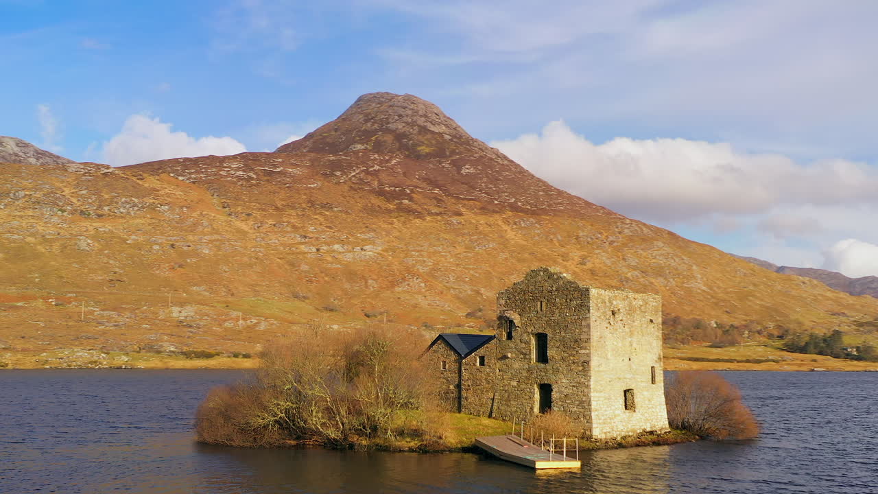Dynamic orbit shot of O'Flaherty Tower House on a sunny day, with Benlettery Mountain in the background.