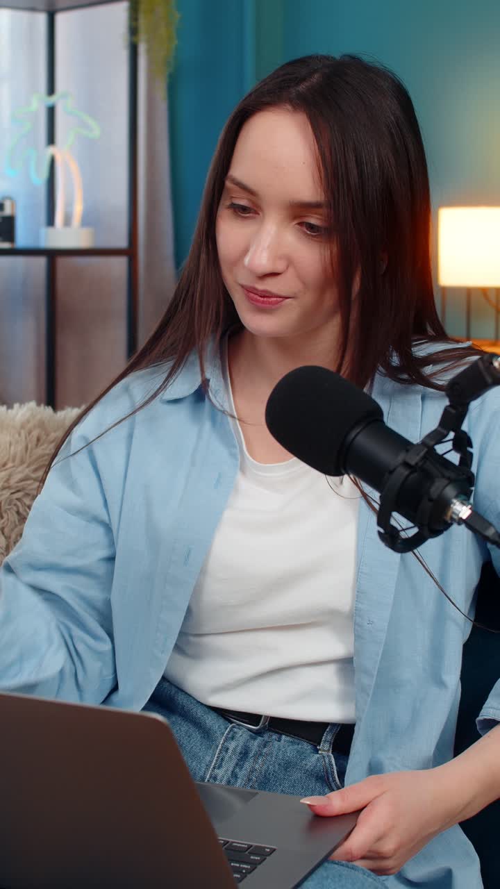 Woman blogger happily recording podcast vlog on sofa actively gesturing telling interesting story