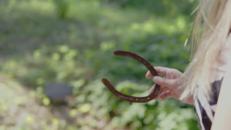 blondie woman removing nail from a rusty horseshoe - close up