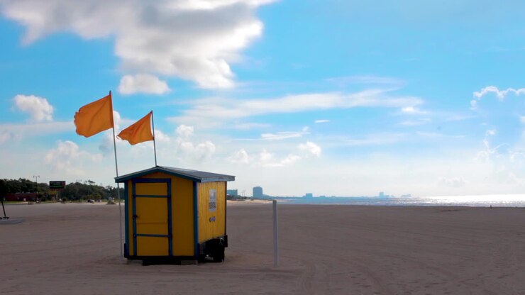 Una capanna sulla spiaggia espone bandiere arancioni su una spiaggia solitaria.