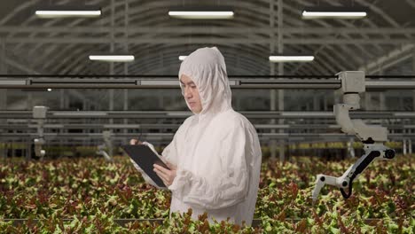 side view of asian man researcher looking around and taking note on a tablet while standing in the greenhouse with smart robotic farmers