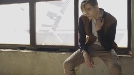 Young-man-sitting-near-window-in-old-room