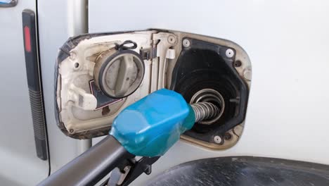 blue fuel nozzle in the tank refilling this vehicle, gas station in thailand