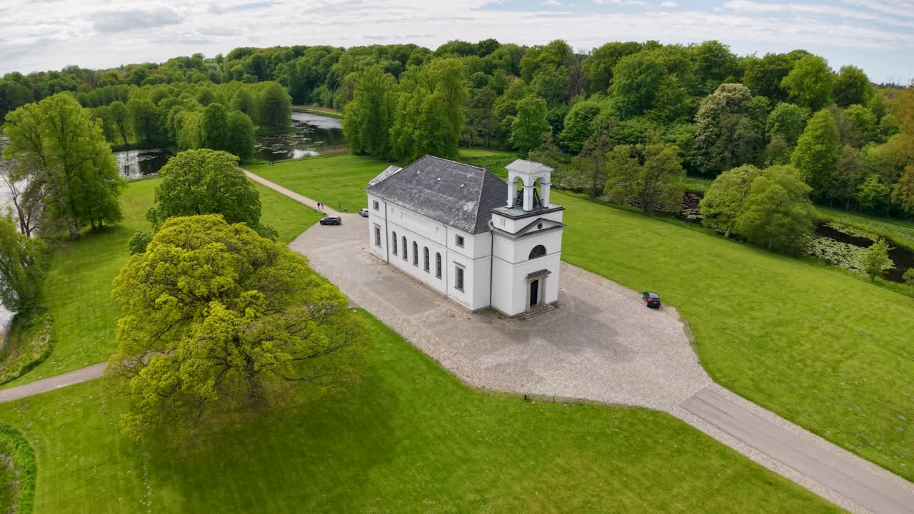 Aerial view of a small white church surrounded by lush green trees in Hørsholm, Denmark