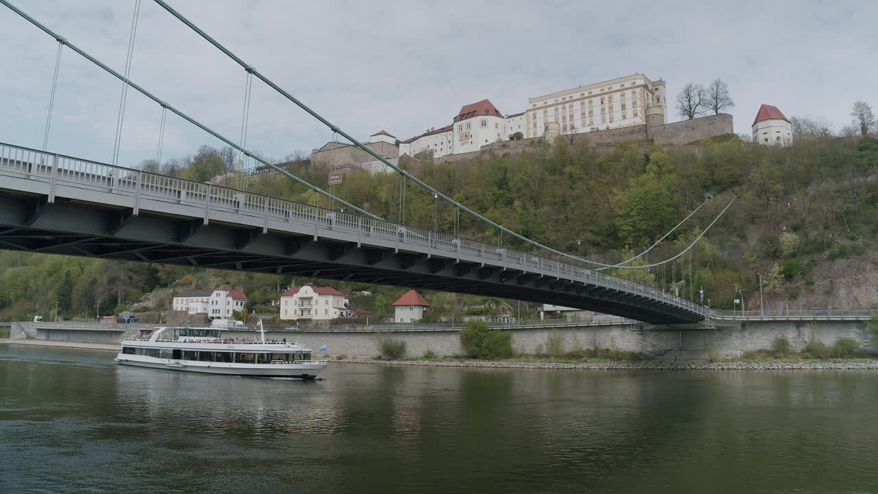 Ship sails under bridge in Passau, calm and scenic, evokes travel vibes