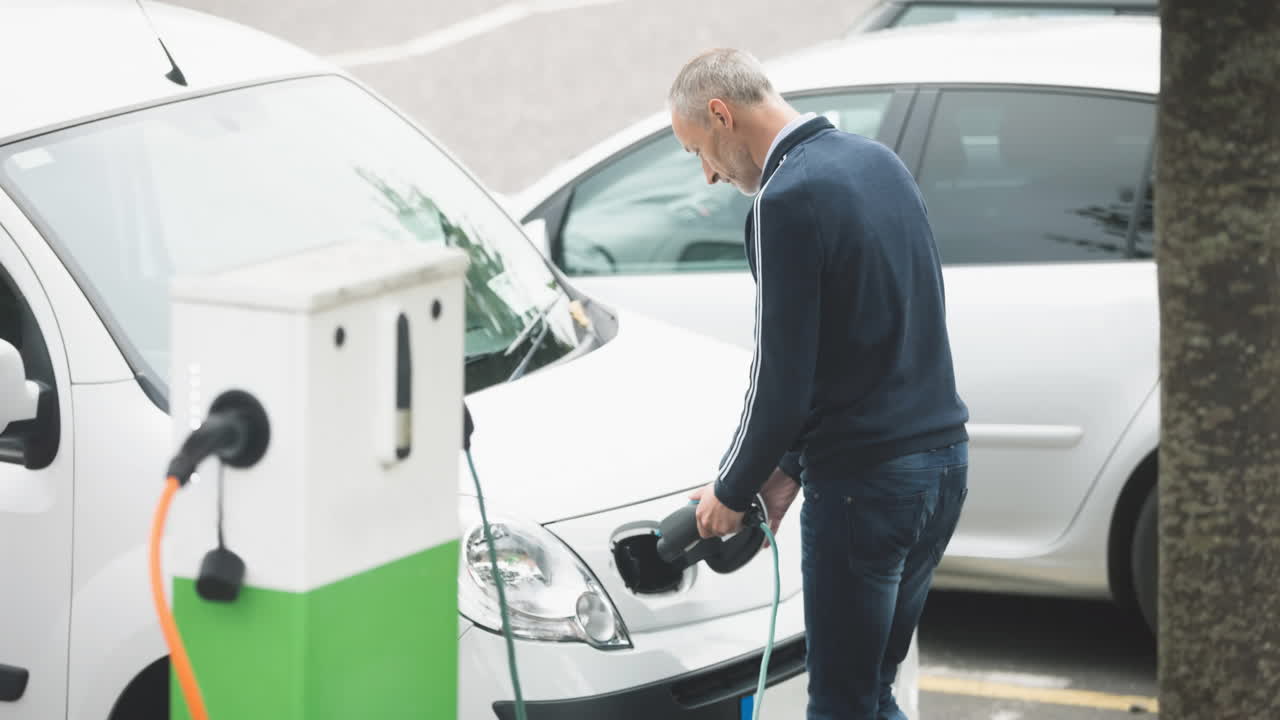 hombre caucásico cargando un coche eléctrico