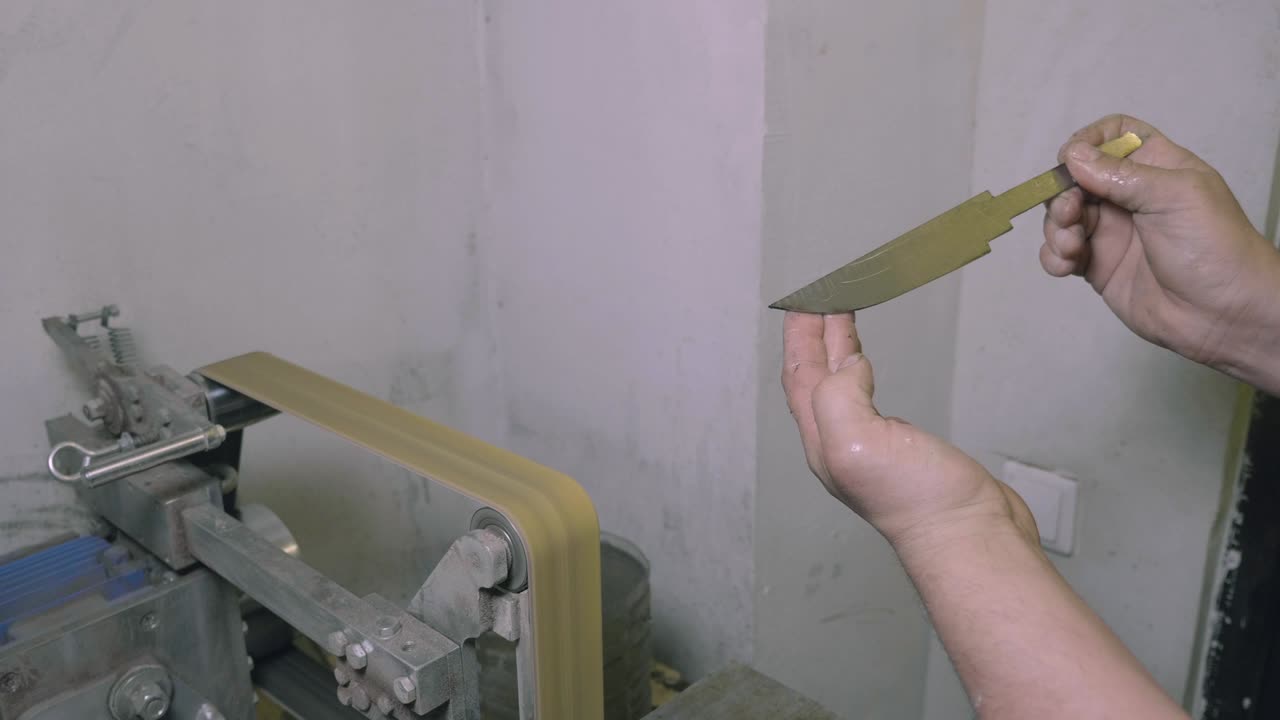 製造ホールで手作りのナイフを握っている従業員